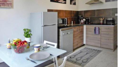une cuisine avec une table et un réfrigérateur blanc dans l'établissement Duplex meublé face aux arènes d'ARLES, à Arles
