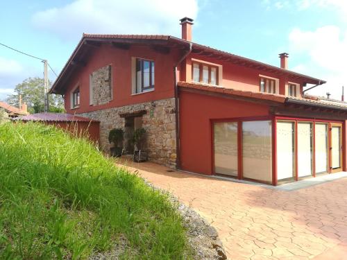 een rood huis met grote ramen op een heuvel bij Casa Rural GAUBEKA in Bakio