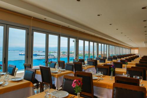 a dining room with tables and chairs and windows at Perla Hotel in Dikili