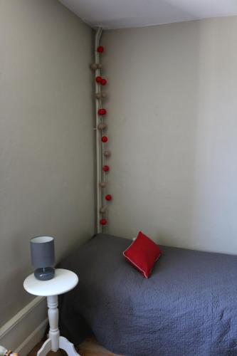 a bedroom with a bed with a red pillow and a stool at Chambres et table L' échappée in Bouvesse-Quirieu