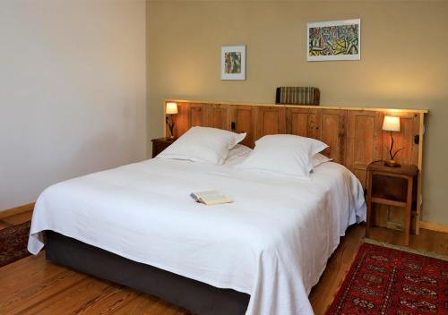 a bedroom with a large white bed with a book on it at l'ancienne gare in Gamarde-les-Bains