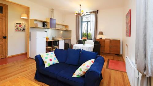 a living room with a blue couch and a kitchen at l'ancienne gare in Gamarde-les-Bains