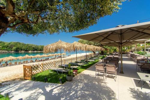 a beach with chairs and tables and umbrellas at Prima Vista Boutique Hotel & Spa in Sivota