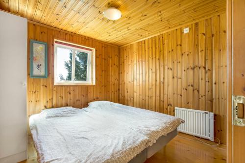1 dormitorio con 1 cama en una pared de madera en Holiday Lakefront house en Björköby