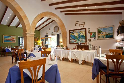 a restaurant with white tables and chairs with blue table cloth at Agroturisme Na Martina in Portopetro