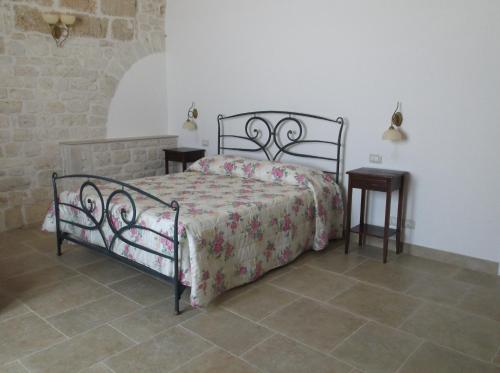 a bed in a room with two tables and a bedspread at Masseria Ciavea in Gioia del Colle