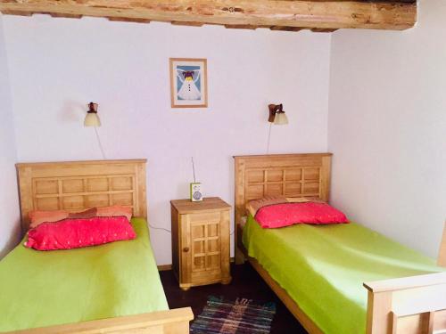 duas camas num quarto com lençóis verdes e vermelhos em Samodzielny Dom Przy Lesie em Tereszewo