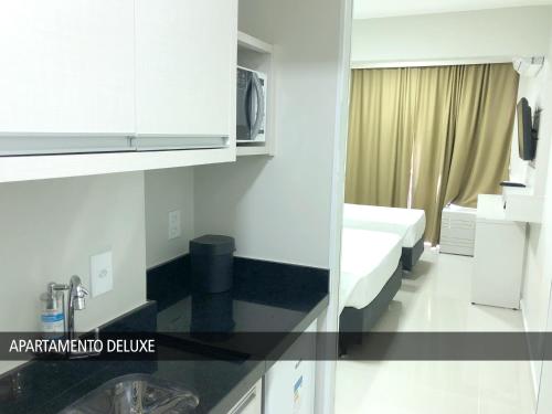 a small kitchen with a sink and a microwave at Nox Apart Hotel - Garvey in Brasilia