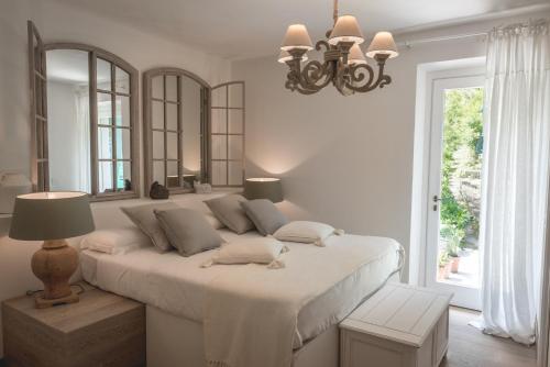 a white bedroom with a large bed and a chandelier at Locanda Senio in Palazzuolo sul Senio