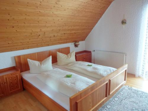 a bedroom with two beds with white sheets and a wooden ceiling at Hochschwarzwald-Hof in Schluchsee
