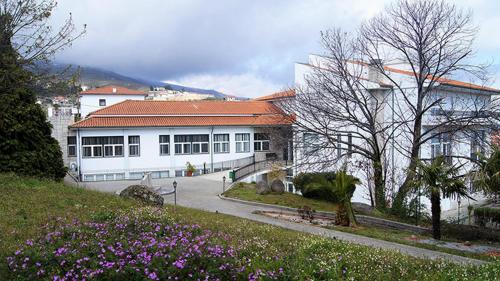 a white building with a red roof and some flowers at Kolping House in Lamego