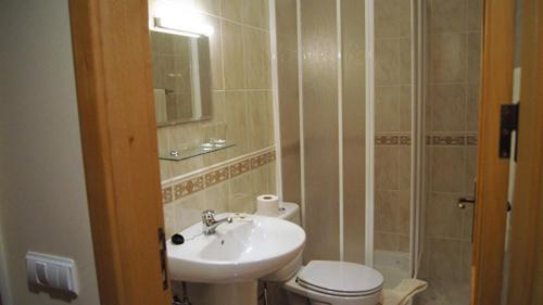 a bathroom with a sink and a toilet and a mirror at Kolping House in Lamego