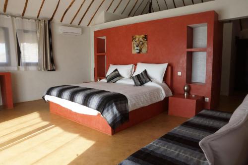 a bedroom with a bed and a red wall at La Taniere Villa Metsu in Saly Portudal