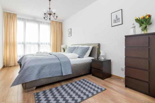 a bedroom with a bed with a dresser and a window at Apartament Wawrzyńca in Krakow
