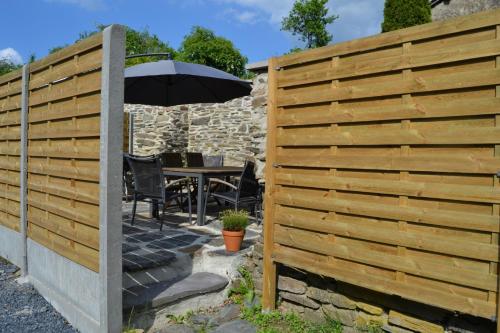 a wooden fence with a table and an umbrella at Gitesonoro Beho in Gouvy