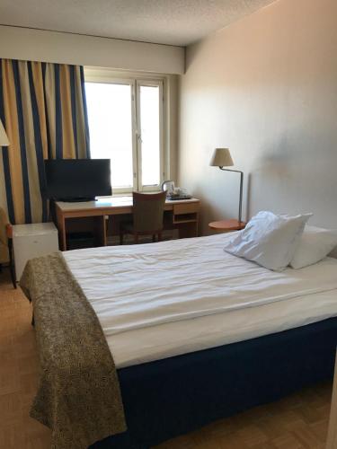 a hotel room with a bed and a desk with a computer at Hotel Hirvi in Äänekoski