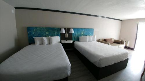 a hotel room with two beds and a chair at Garden City Inn in Myrtle Beach