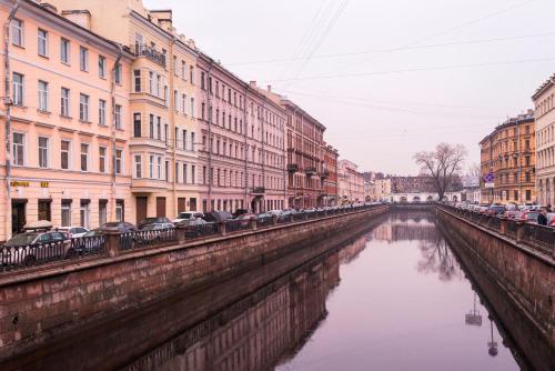 ein Fluss in einer Stadt mit Gebäuden und Autos darauf in der Unterkunft Итальянские комнаты Пио на канале Грибоедова 35 in Sankt Petersburg