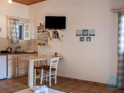 a kitchen with a table and a tv on the wall at Astra Studios in Astypalaia Town