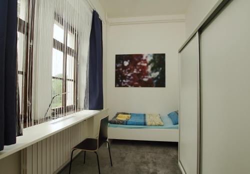 a small bedroom with a bed and two windows at Koleje Zamecek in Lednice