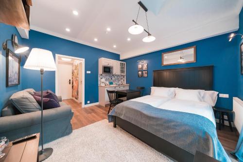 a bedroom with blue walls and a bed and a couch at Revelton Studios Františkovy Lázně in Františkovy Lázně