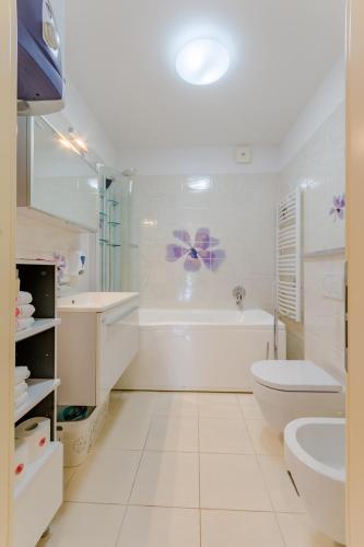 a white bathroom with a tub and a toilet and a sink at Apartments Villa Camellia - Adults Only, no parking in Supetar