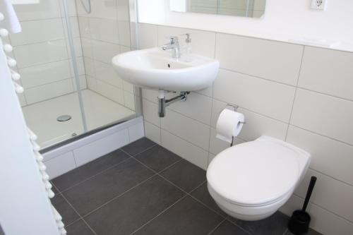 a white bathroom with a toilet and a sink at Motel Schönefeld in Großziethen