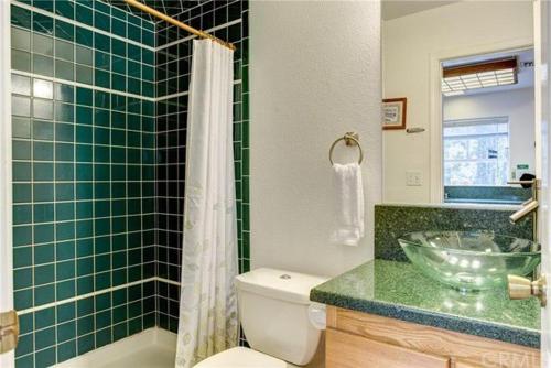 La salle de bains carrelée de couleur verte est pourvue d'un lavabo et de toilettes. dans l'établissement Jumping Deer, à Yosemite West