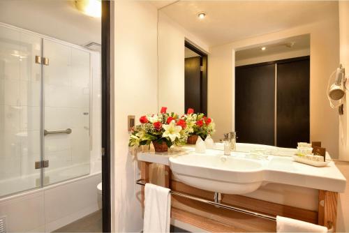 a bathroom with a sink and a shower with flowers at Hotel Eurotel Providencia in Santiago