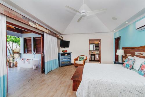 a bedroom with a bed and a bathroom with a tub at Hermosa Cove Villa Resort & Suites in Ocho Rios