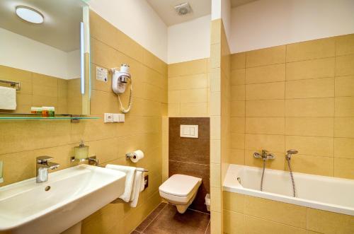 a bathroom with a sink and a toilet and a tub at Hotel Iberia in Opava