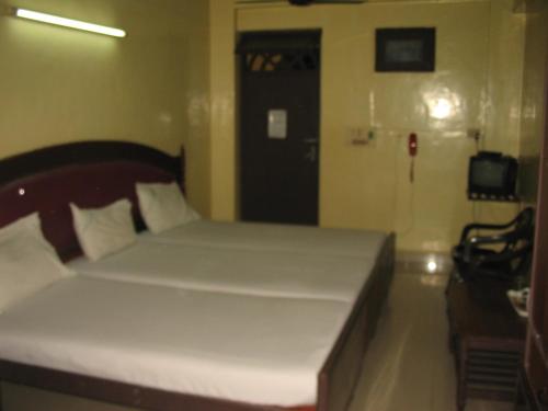 a bedroom with a bed and a door with a chair at Hotel Sorrento Guest house Anna Nagar East Metro Shenoy Nagar metro budget monthly daily rooms in Chennai