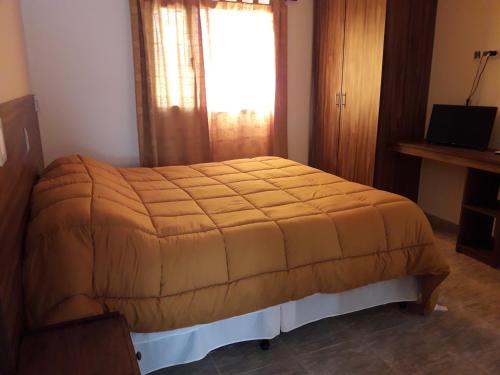 Un dormitorio con una cama con una manta naranja. en Tierra Virgen Cabañas, en San Rafael