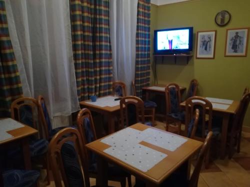 a dining room with tables and a tv on the wall at Penzión Rodina in Levoča