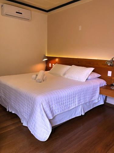 a bedroom with a large bed with white sheets at Pousada Vovô Chiquinho in Tiradentes
