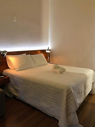 a bedroom with a large bed with a white blanket at Pousada Vovô Chiquinho in Tiradentes