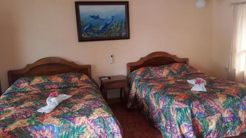 two beds in a hotel room with towels on them at Cabinas Doña Alicia in Quepos