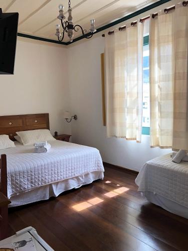 a bedroom with two beds and a television in it at Pousada Vovô Chiquinho in Tiradentes