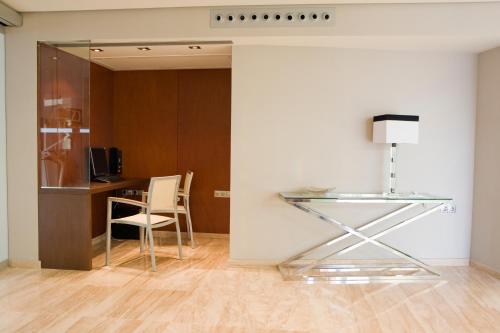 a glass table and a chair in a room at Hotel y Apartamentos Conilsol in Conil de la Frontera