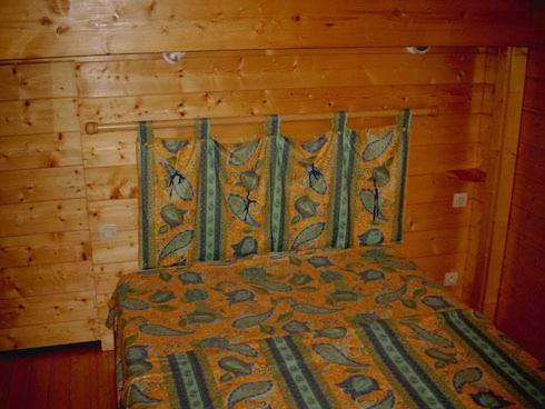 ein Schlafzimmer mit einem Bett mit einer Holzwand in der Unterkunft Chalet Helalph in La Bresse
