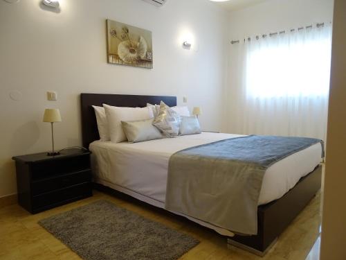 a bedroom with a bed with white sheets and a window at Casa Afonso Henriques in Burgau