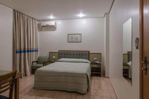 a small bedroom with a bed and a chair at Cinelandia Hotel in Sao Paulo