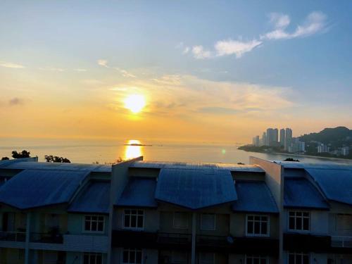 a building with a sunset in the background at Shamrock Boutique Villa in Batu Ferringhi