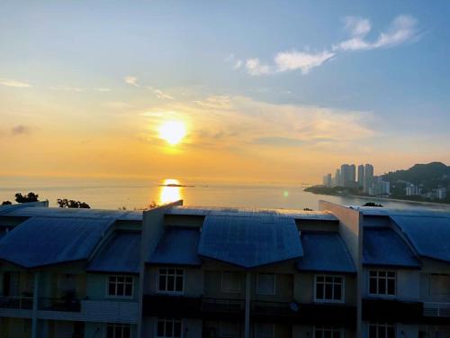 a building with a sunset in the background at Shamrock Boutique Villa in Batu Ferringhi