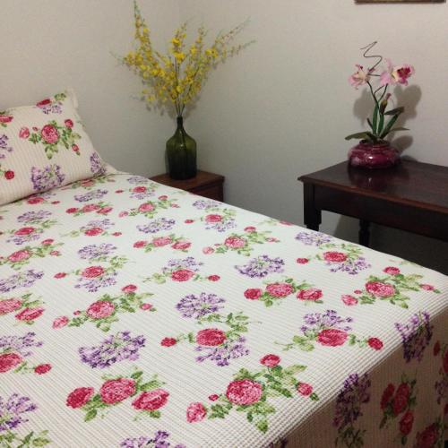 Una cama con una manta con flores. en Espaco unico, en São José do Rio Preto