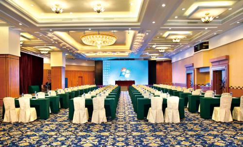 um grande salão de banquetes com mesas verdes e cadeiras brancas em Guangdong Hotel (Zhuhai) em Zhuhai