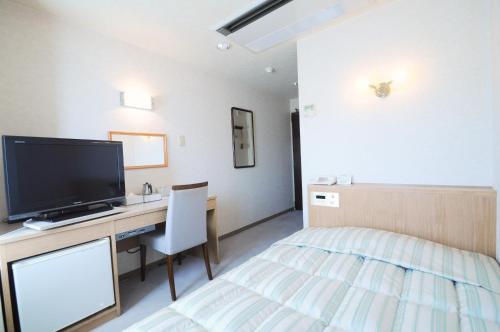 a hotel room with a bed and a television at Hotel New Chikou in Wakkanai