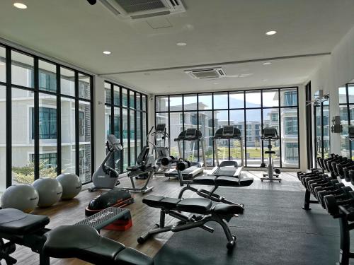 a gym with several treadmills and exercise bikes in a room with windows at The Meadow Park in Kampar