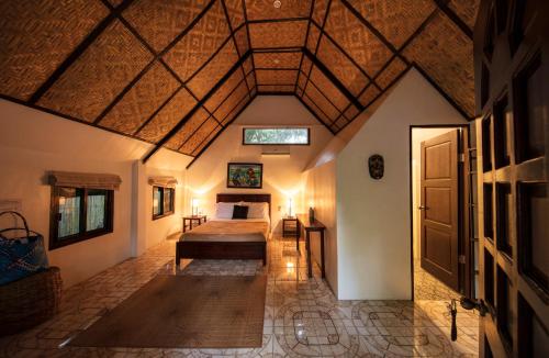 ein Schlafzimmer in einem Haus mit einem Bett und einer Tür in der Unterkunft Cabilao Sanctuary Beach & Dive Resort in Loon