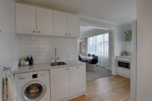 a kitchen with white cabinets and a sink and a dishwasher at River Retreat in Gore